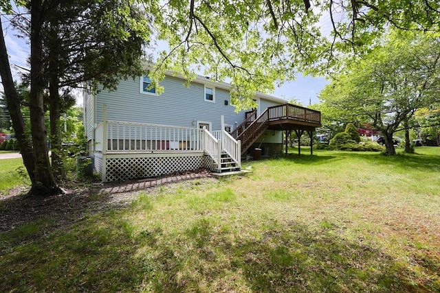 back of property with stairway, a deck, and a lawn