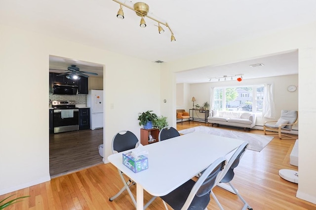 dining space with track lighting, light wood-style flooring, and ceiling fan