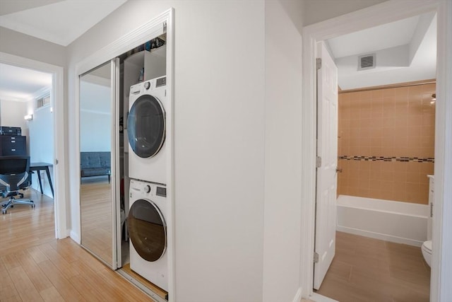 washroom featuring light hardwood / wood-style floors and stacked washer / dryer