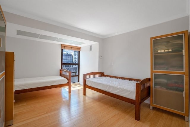 bedroom featuring ornamental molding and light wood-type flooring