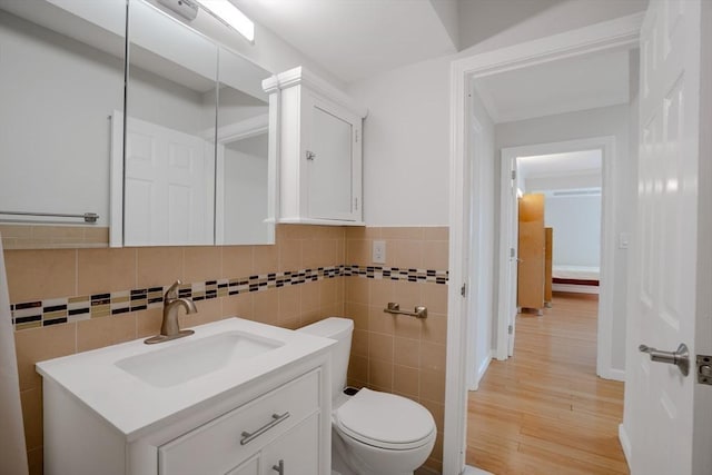 bathroom with hardwood / wood-style flooring, vanity, tile walls, and toilet