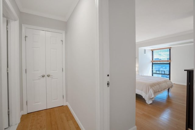 corridor with ornamental molding and light hardwood / wood-style floors