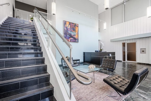 stairway featuring a towering ceiling and wooden walls