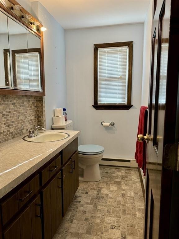 bathroom with vanity, backsplash, baseboard heating, and toilet