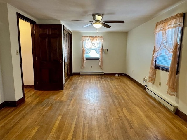 spare room with ceiling fan, baseboard heating, and light hardwood / wood-style flooring