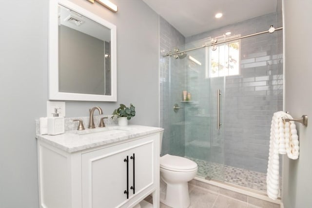 bathroom with vanity, toilet, a shower with shower door, and tile patterned flooring