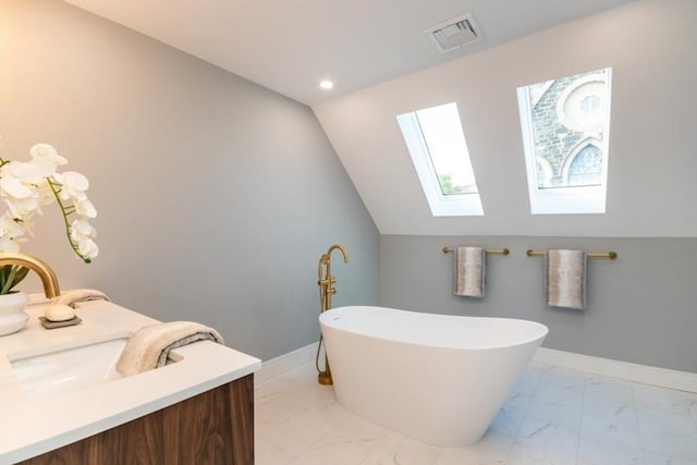 bathroom featuring a tub to relax in, vanity, and lofted ceiling with skylight