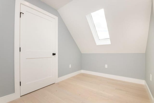 bonus room featuring lofted ceiling with skylight and light hardwood / wood-style floors