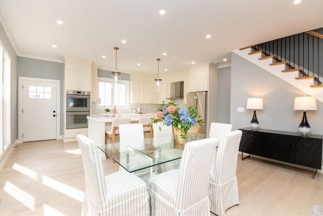 dining area with crown molding and light hardwood / wood-style flooring