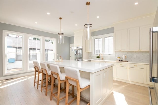 kitchen featuring double oven, hanging light fixtures, tasteful backsplash, ornamental molding, and a kitchen island