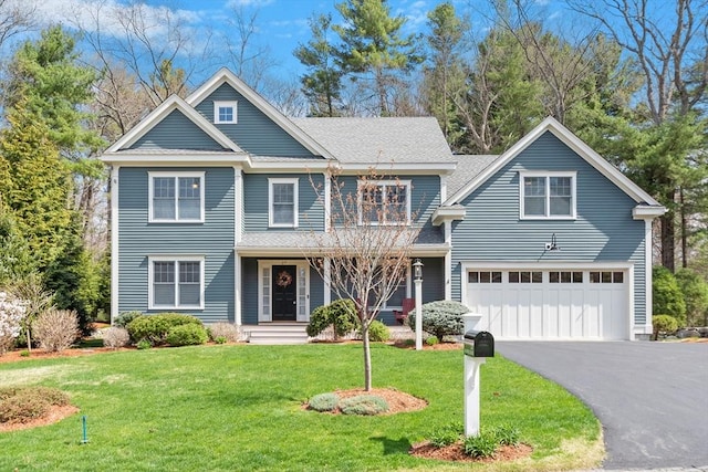view of front of house with a garage, driveway, a front yard, covered porch, and a shingled roof