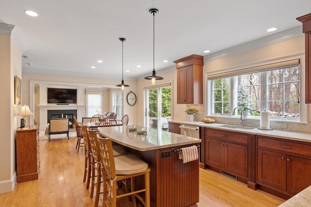 kitchen featuring a sink, a fireplace, light stone countertops, a breakfast bar, and backsplash