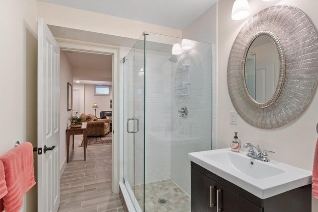 full bathroom with a stall shower, vanity, and wood finished floors