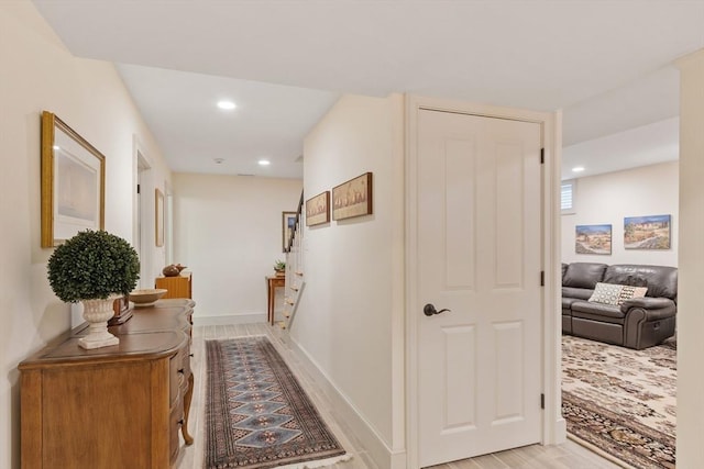 hallway with light wood-type flooring, recessed lighting, and baseboards