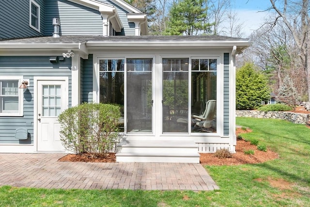 property entrance with a lawn and roof with shingles