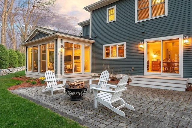 rear view of property with an outdoor fire pit, a sunroom, and a patio area