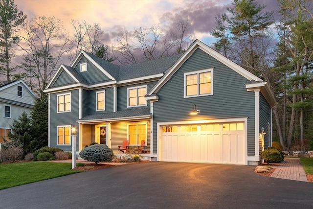 view of front facade featuring driveway, an attached garage, and covered porch