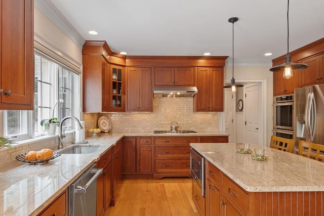 kitchen featuring a sink, brown cabinets, appliances with stainless steel finishes, light wood-style floors, and under cabinet range hood