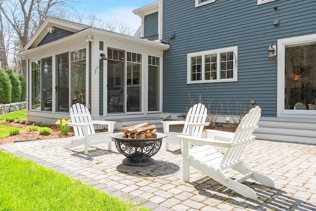 view of patio / terrace featuring a sunroom and an outdoor fire pit