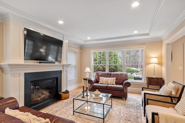 living area with light wood-style floors, a large fireplace, crown molding, recessed lighting, and baseboards