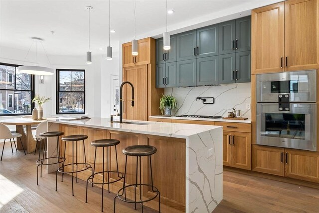 43 Wendell St Unit 0, Cambridge, MA 02138 - kitchen featuring white gas stovetop, tasteful backsplash, light stone counters, a sink, and light wood finished floors