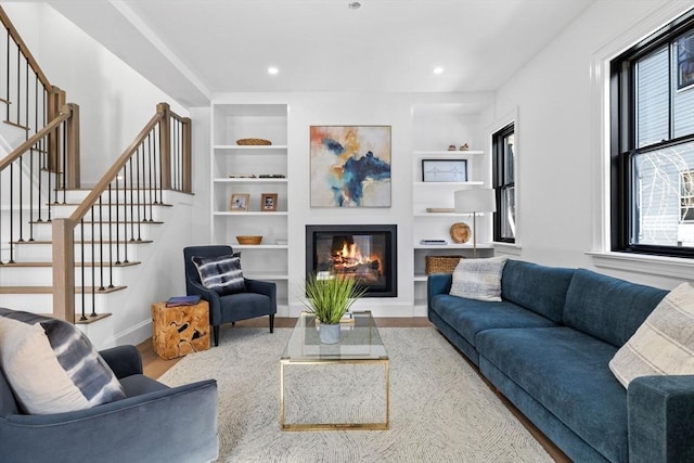 43 Wendell St Unit 0, Cambridge, MA 02138 - living room featuring built in shelves, wood finished floors, baseboards, a glass covered fireplace, and stairs