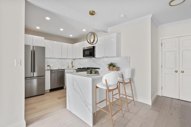 85 E India Row Unit 36D, Boston, MA 02110 - kitchen featuring appliances with stainless steel finishes, a peninsula, crown molding, a breakfast bar, and light wood finished floors