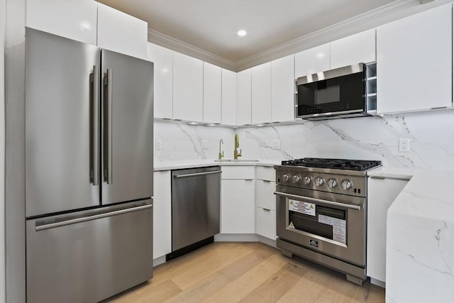 85 E India Row Unit 36D, Boston, MA 02110 - kitchen featuring appliances with stainless steel finishes, a sink, white cabinets, light wood-style flooring, and light stone countertops