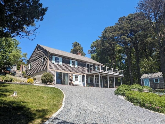 view of front of home featuring a balcony, an outdoor structure, and a front yard