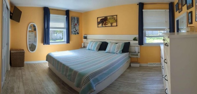 bedroom with hardwood / wood-style floors and multiple windows