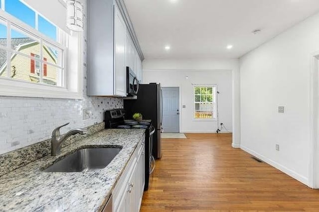 18 Anderson St, Lowell, MA 01852 - kitchen featuring black electric range, a sink, light wood-style flooring, recessed lighting, and tasteful backsplash