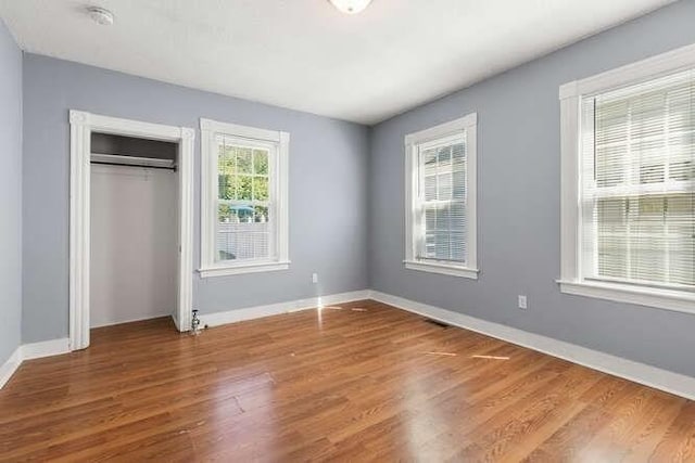 18 Anderson St, Lowell, MA 01852 - unfurnished bedroom featuring wood finished floors, baseboards, and a closet