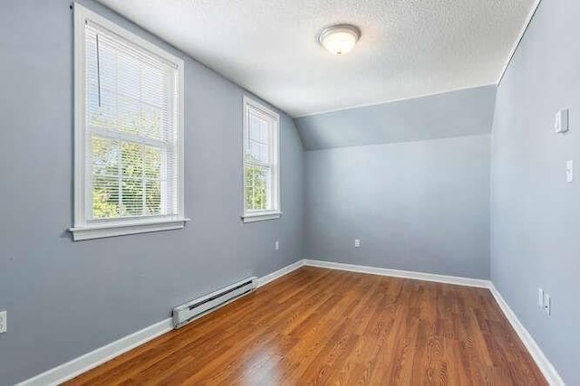 18 Anderson St, Lowell, MA 01852 - bonus room featuring baseboard heating, wood finished floors, vaulted ceiling, baseboards, and a textured ceiling