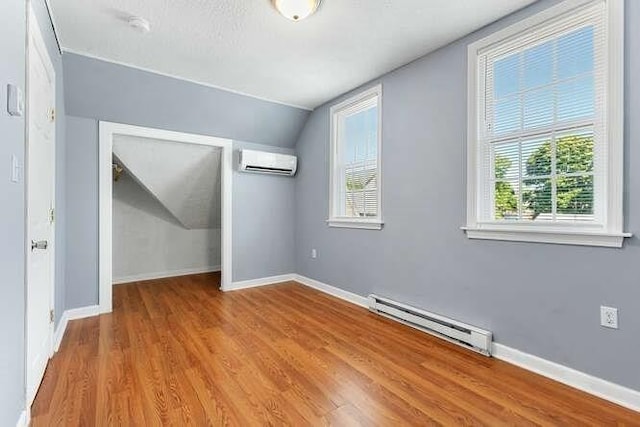 18 Anderson St, Lowell, MA 01852 - unfurnished bedroom featuring baseboard heating, an AC wall unit, lofted ceiling, wood finished floors, and a closet