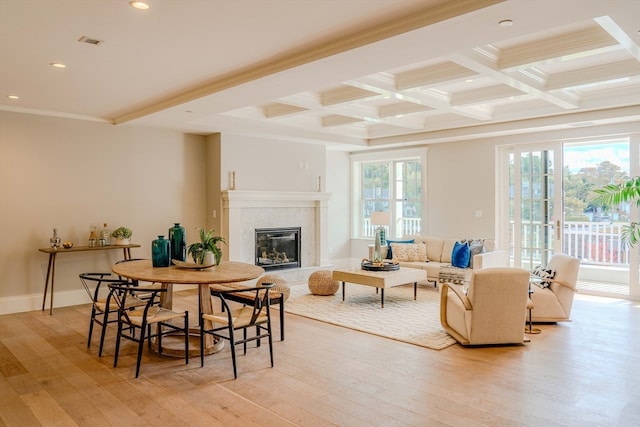 living room featuring coffered ceiling, crown molding, light wood-type flooring, beamed ceiling, and a high end fireplace