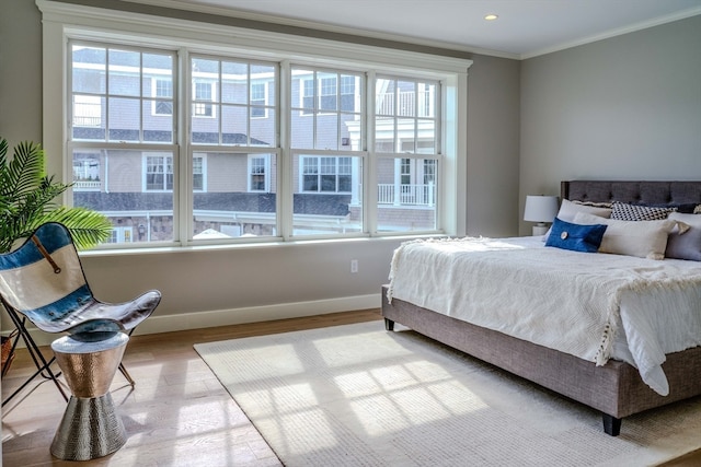 bedroom featuring hardwood / wood-style flooring, ornamental molding, and multiple windows