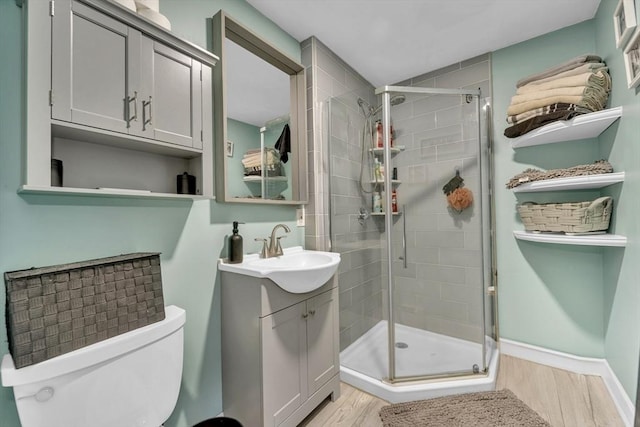 full bath with wood finished floors, a shower stall, vanity, and toilet