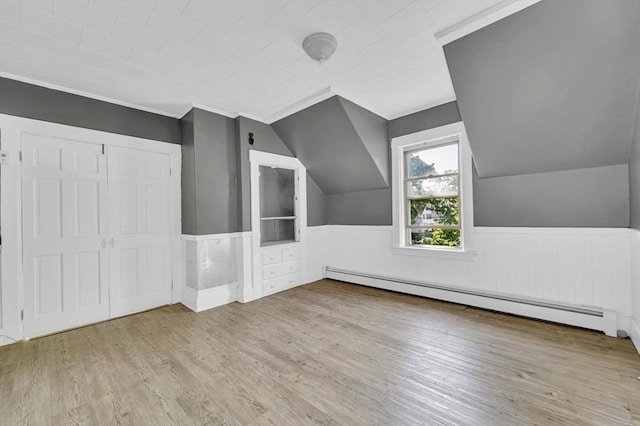 additional living space featuring baseboard heating, wood finished floors, built in features, wainscoting, and lofted ceiling