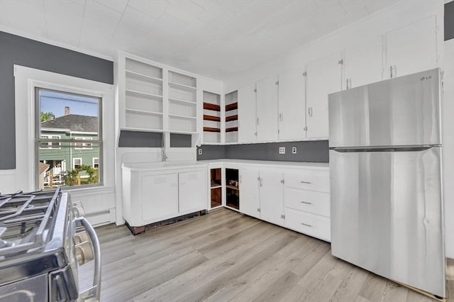 kitchen featuring stainless steel appliances, light wood finished floors, white cabinetry, and light countertops