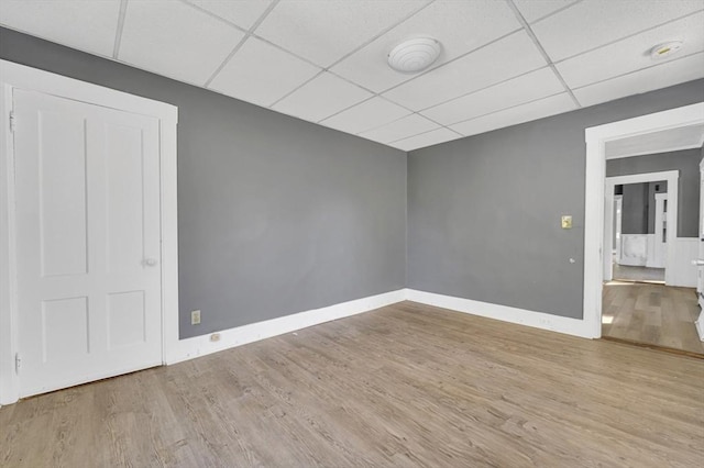 spare room featuring a paneled ceiling, wood finished floors, and baseboards