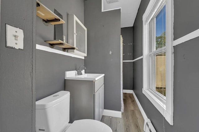 bathroom with wood finished floors, toilet, vanity, baseboards, and a baseboard radiator