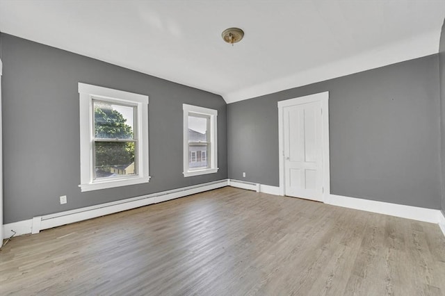 empty room with baseboard heating, wood finished floors, and baseboards