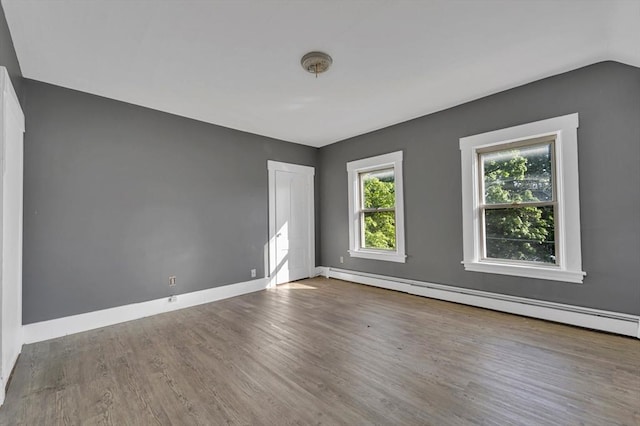 unfurnished room with a baseboard heating unit, wood finished floors, baseboards, and lofted ceiling