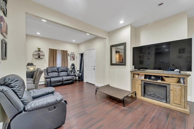 living room with dark wood-style flooring, recessed lighting, a baseboard heating unit, a glass covered fireplace, and baseboards