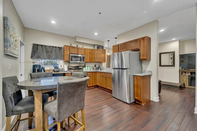 kitchen with stainless steel appliances, dark wood finished floors, brown cabinetry, and recessed lighting