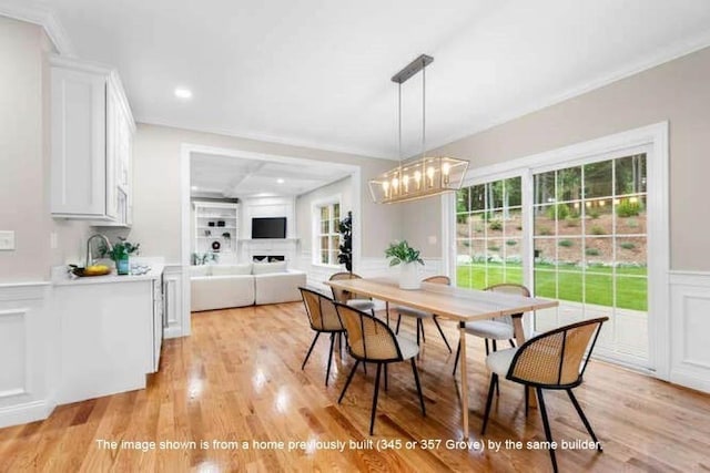 363 Grove St, Reading, MA 01867 - dining area with a decorative wall, light wood finished floors, a wainscoted wall, a chandelier, and a fireplace