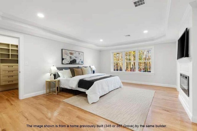 363 Grove St, Reading, MA 01867 - bedroom featuring a tray ceiling, light wood-type flooring, a glass covered fireplace, recessed lighting, and a spacious closet