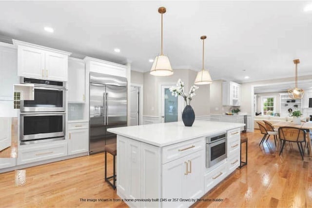 363 Grove St, Reading, MA 01867 - kitchen with appliances with stainless steel finishes, white cabinetry, light countertops, open floor plan, and recessed lighting