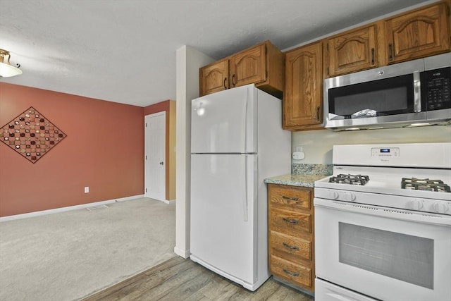 125 Chapin Rd Unit 3F, Hudson, MA 01749 - kitchen featuring white appliances, brown cabinets, baseboards, light wood-type flooring, and light stone countertops