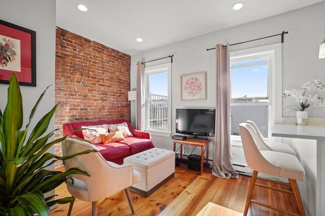 living room with brick wall, light hardwood / wood-style flooring, and a baseboard radiator